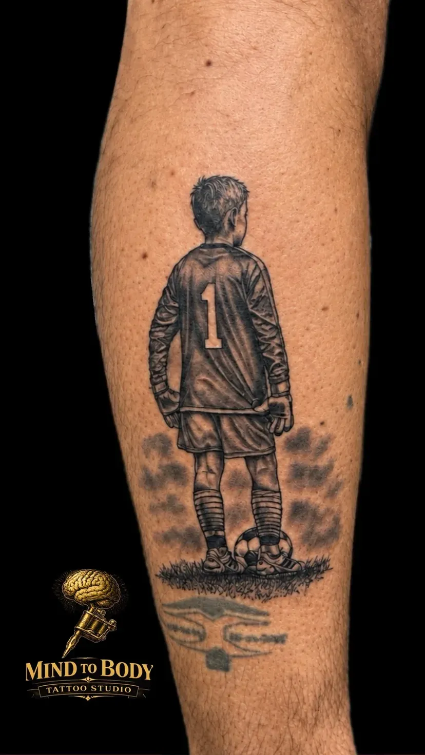 Black and grey realistische tattoo van een jonge voetballer met rugnummer 1 op de kuit, tattoo Gent