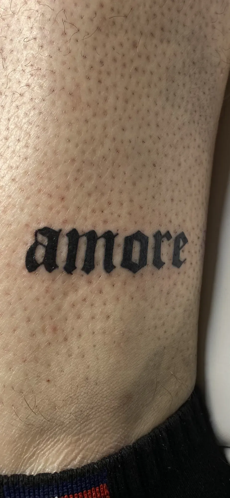 Blackletter lettering amore op de ribbenkast, tattoo Gent