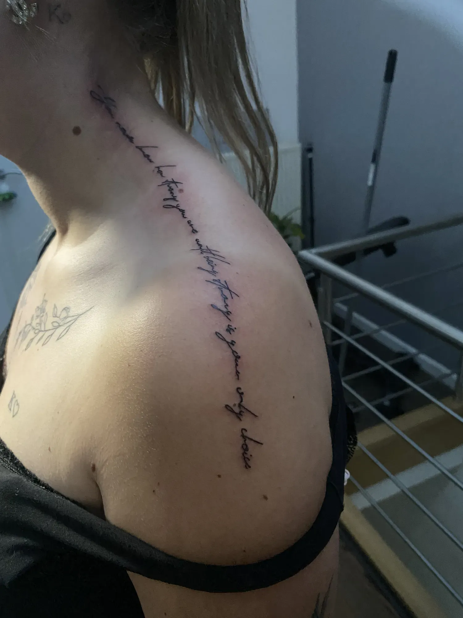 Sierlijk lettering-citaat op de schouder, tattoo Gent