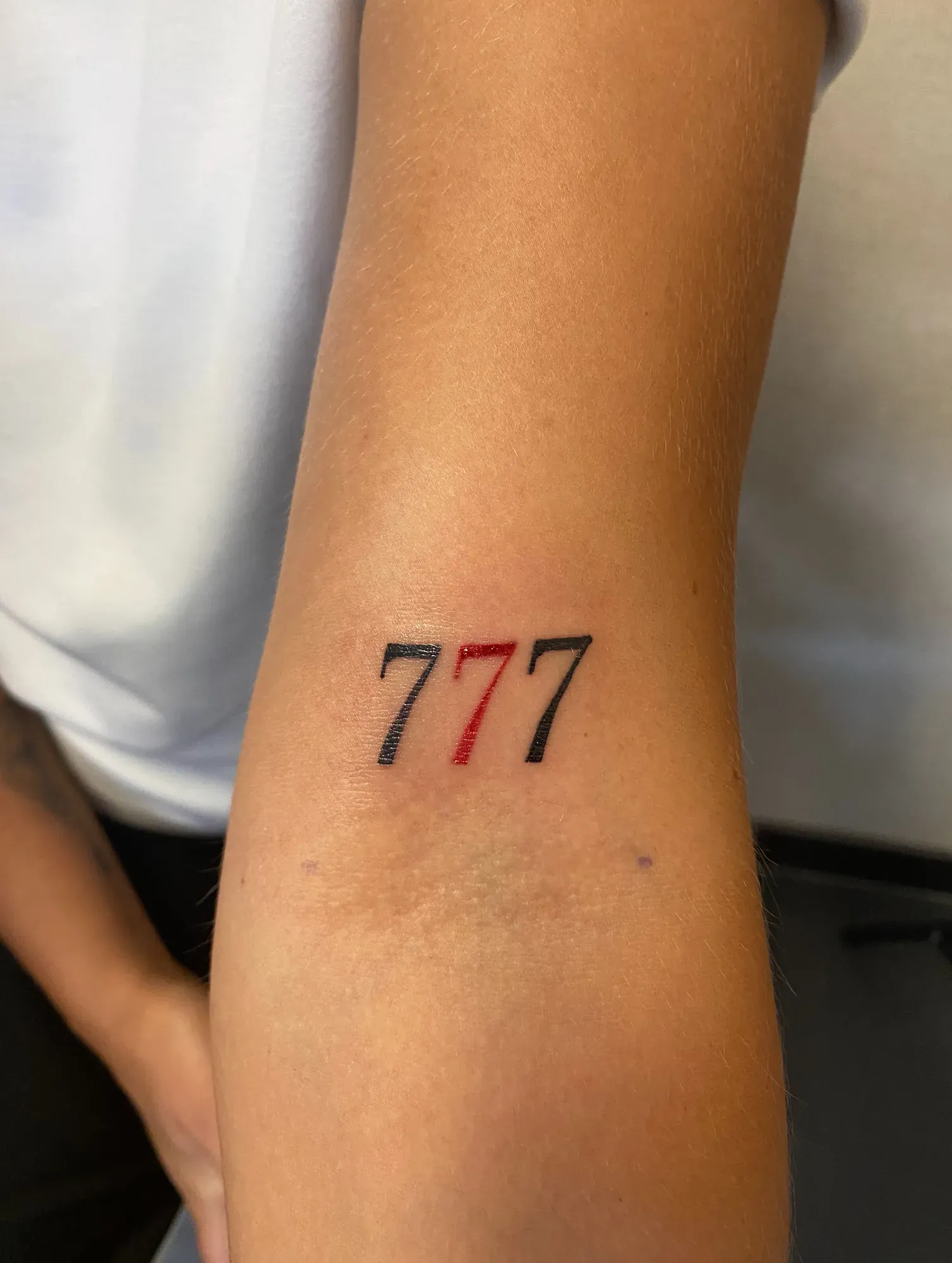 Lettering 777 in rood en zwart op de arm, tattoo Gent